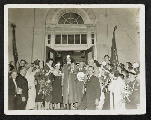 Mrs. Eleanor Roosevelt standing at a microphone, giving a speech to an unidentified group of people