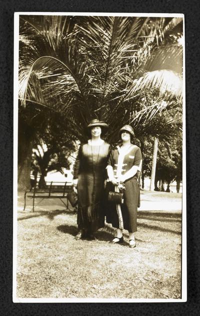 Cora Wilson Stewart and an unidentified female standing under a palm tree