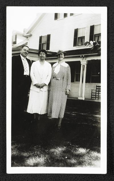 Cora Wilson Stewart posing for a photograph with an unidentified couple, standing in front of a white house