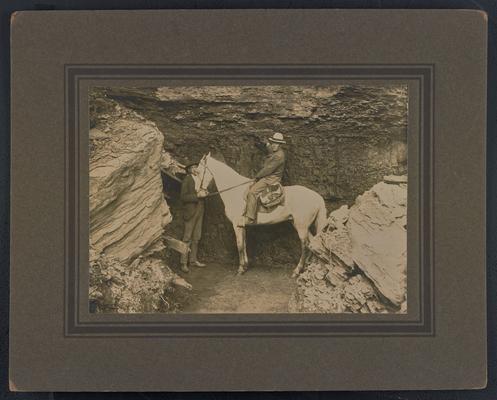 Two unidentified males, one standing and one on a horse, in front of a coal seam. Back of the photograph reads: A seven foot vein of coal in the mountains of northeastern Kentucky