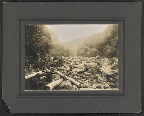 Large rocks and logs at the base of surrounding mountains and trees. Bottom of the photographs reads: In the 'Breaks' of Big Sandy