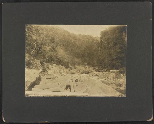 Large rocks and logs at the base of a mountain. Back of the photograph reads: Scene at the Breaks of Big Sandy River