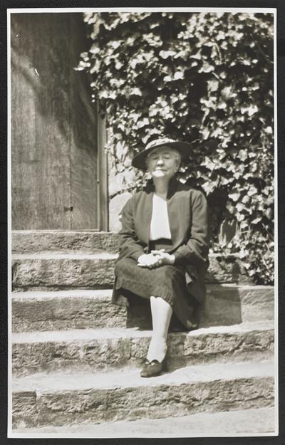 Cora Wilson Stewart as an elderly woman, sitting on the front steps of a house