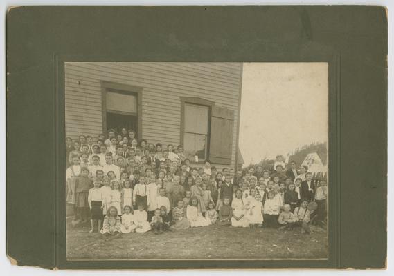Unidentified young students posing outside of the school house