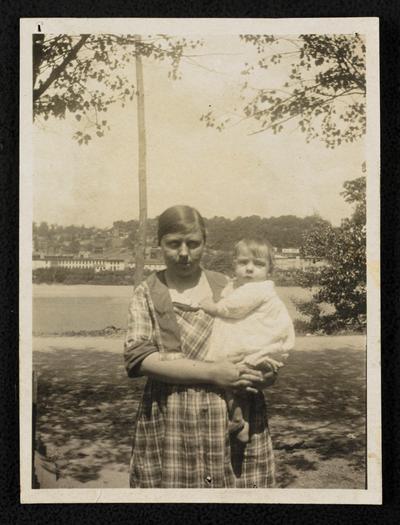 Woman holding a baby outside, back of the photograph reads: Learning for baby's sake