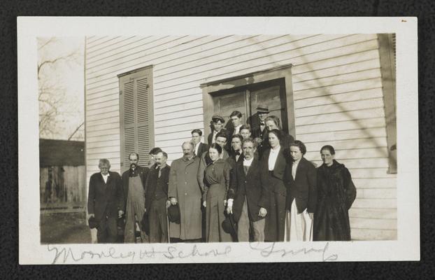 Adult students in front of a school house, written under the picture:Moonlight School Group
