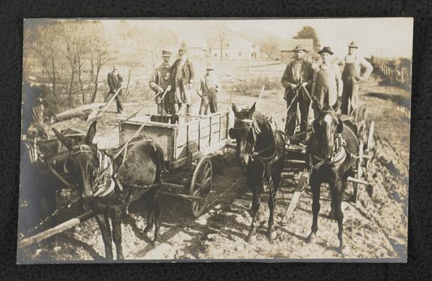 Unidentified men standing in wagons while working on the model road in front of Alfrey School. Similar photograph to item 511