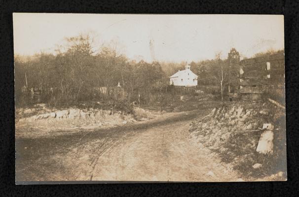 Road leading up to a white building (possibly a school house) in the distance, similar image to item 545, location unknown