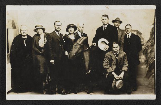 Postcard of unidentified men and women, and Cora Wilson Stewart, from the Democrator National Convention. One man is sitting on a fake donkey. The back of the card reads: Compliments of Cora Wilson Stewart