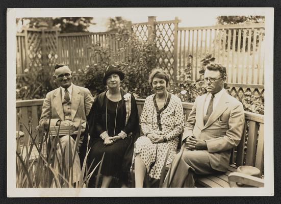 Cora Wilson Stewart, seated and posing with a woman and two men. The back of the photograph reads: Visit to Lafayette of Mrs. Cora Wilson Stewart, 'The Lady of the Moonlight Schools' encouraging the education of adult illiterates. Left to right: Dr. M. S. Robertson, State Department of Education; Mrs. Stewart, Mrs. Stephens, Parish Superintendent J.W. Faulk. -Compliments of President Stephens, For Mrs. Stewart May 1929