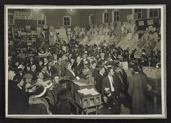 An unidentified group of people in an unidentified location, looking at crafts made from different schools