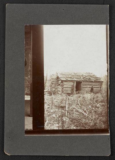 Unidentified woman with two children in front of a cabin, back of the photograph reads: Use only one of these cabins