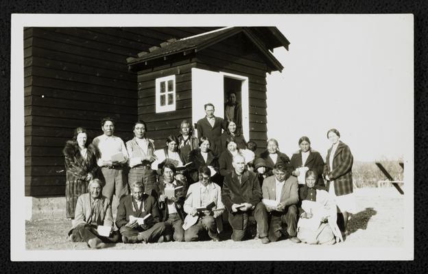 Group from the illiteracy class on the Blackfeet Reservation, holding books. Back of the photograph reads: Little Badger School