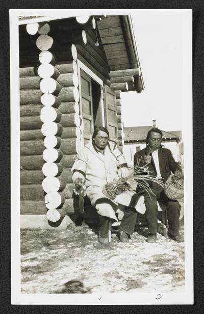 Two males sitting, smoking pipes, and weaving baskets. Back of the photograph identifies them as: 1. Albert Mad Plume or Black Owl 2. James Spotted Eagle