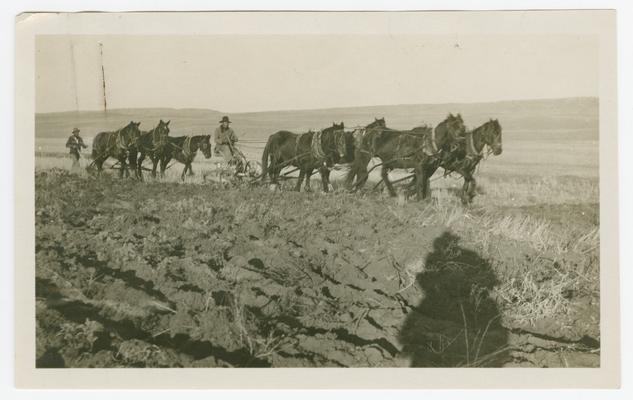 Two men using a horse and plow in a field. Handwritten note with the photograph reads: Elmer Rattler- riding plow. George Mad Plume- walking plow. Thought you might use this in illustrating the plow lesson