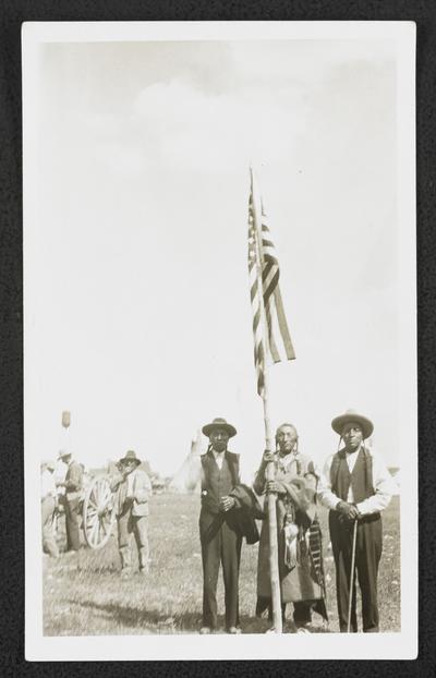 Men standing around a flagpole with the American flag, photograph was printed in Havre, Montana on July 8, 1925