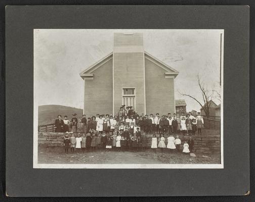 Large unidentified group, mainly children, standing outfront of a building