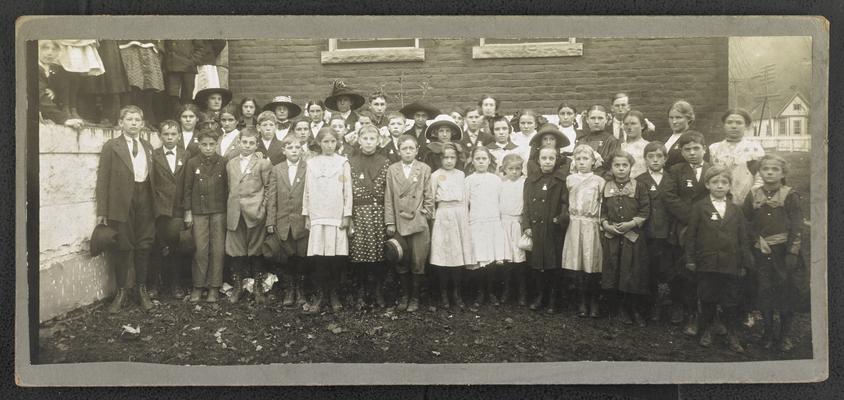 Young students posing for picture in front of school building