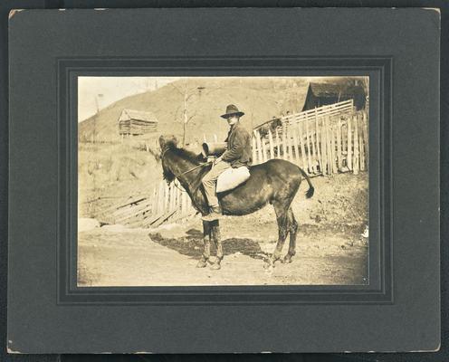 Unidentified man riding a horse. The back of the photograph reads: The Mountain Child- His environment. Slow transportation impedes progress
