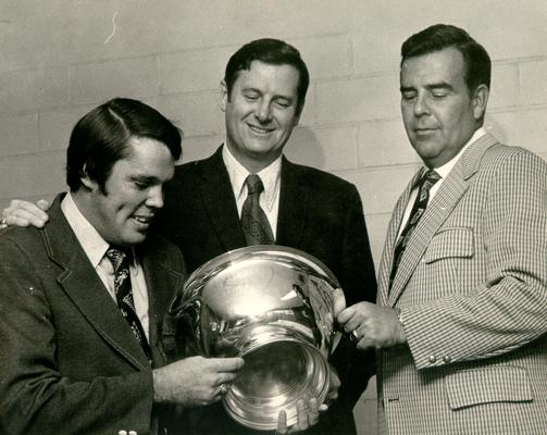 Hall, Joe B.; Joe B. Hall looking at a trophy with two other men