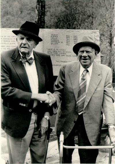 Hatfield; McCoy Monument; Two men shake hands in front of the Hatfield; McCoy monument