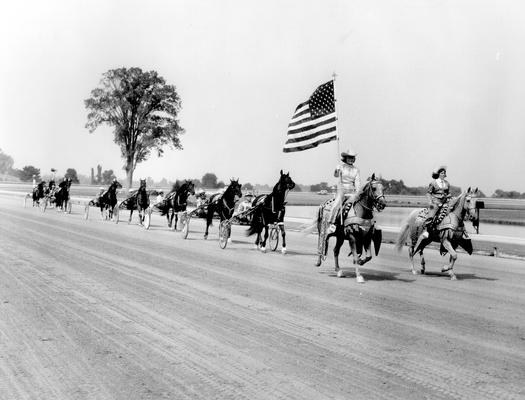 Horses; Harness Racing; Race Scenes; Two decorated horses and the American flag lead the racers down the track