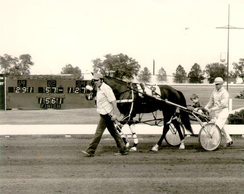 Horses; Harness Racing; Race Scenes; Two men help a young boy ride a horse