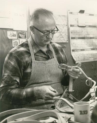 Horses; People Working with Tack and Horse Accessories; A man examining his work