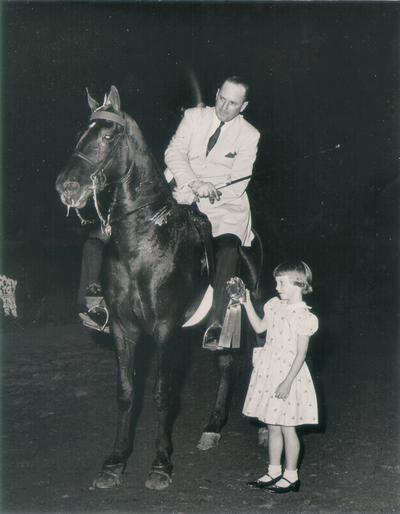 Horses; Show Horses and Jumpers; Little girl presenting a ribbon to a show horse