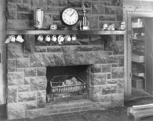 Interiors of Rooms; A clock and a set of tea cups hang over a fireplace