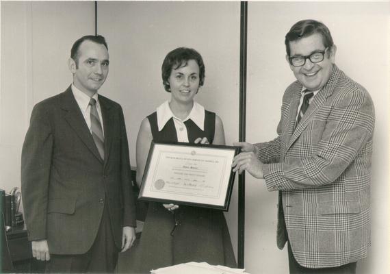 Kentucky Central Life Insurance Company; A female employee holds her degree while posing with two male colleagues