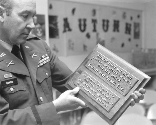 Kentucky Easter Seal Society; National Guard Member, Buntin, holding a plaque