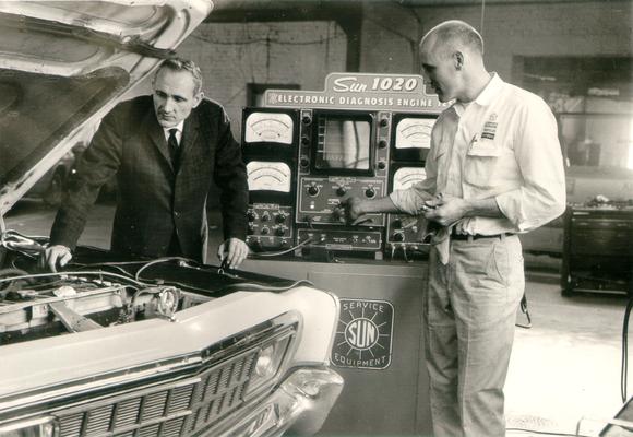 Machines and Machine Parts; Two men hooking a car up to the