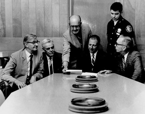 Men; Groups; Unidentified; A Lexington City Policeman watches over a business meeting