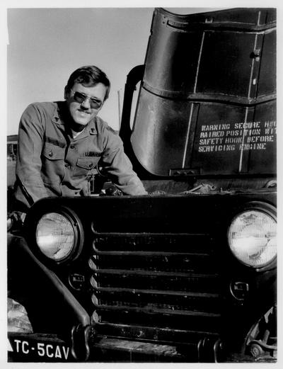 Men; Individual; Unidentified; A man working on an engine of an Army Jeep