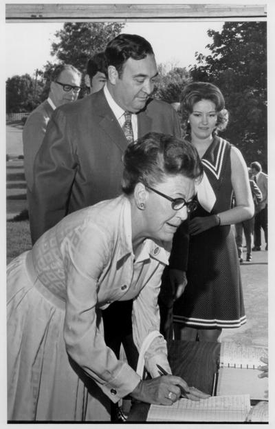 Nunn, Louie B.; Mrs. Nunn signs something, while her husband looks on