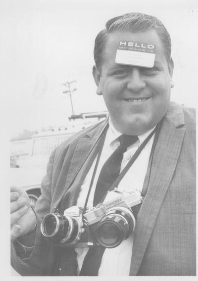 Photographers; Reporter Frank Anderson wearing a name tag on his head