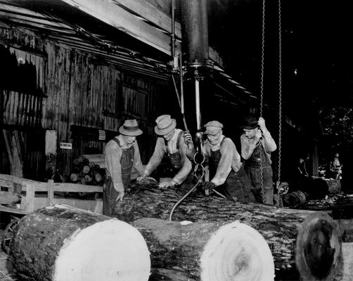 Sawmill; Four men fix a hoist onto a log at saw mill