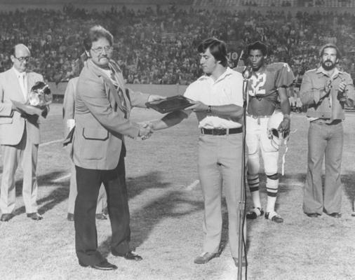 University of Kentucky; Football; Small Group & Team; A man presenting an award on the field