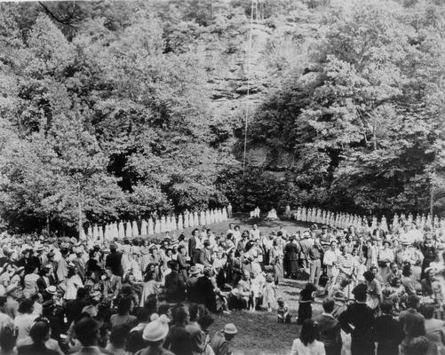 Beauty pageants; Outdoor gathering, contestants lined up beneath a rock wall