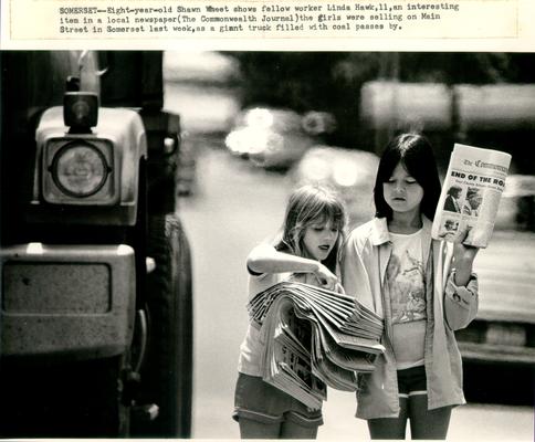 Children; Two kids read a newspaper