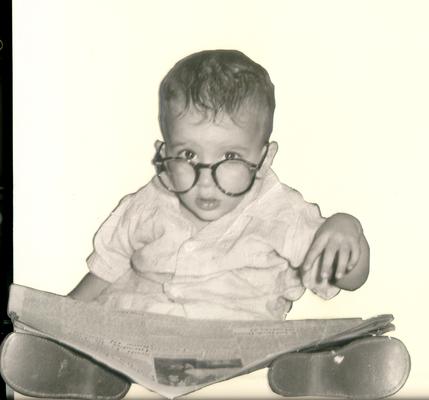 Children; Boy in oversized glasses, looking at a newspaper (cutout)
