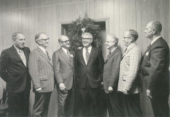 Groups; Unidentified; Seven associates in front of a wreathed door