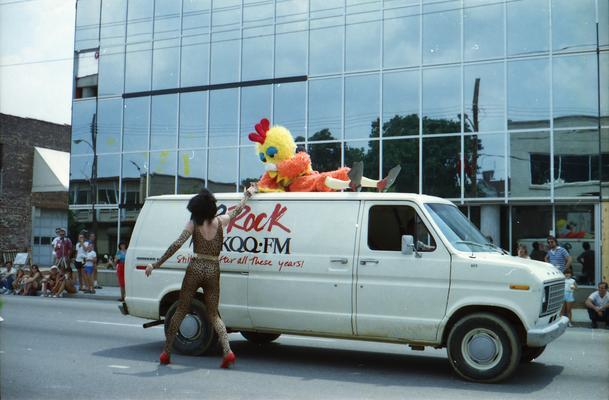 WKQQ Lexington Rock radio station van, chick mascot, and person in drag at the Lexington Fourth of July parade