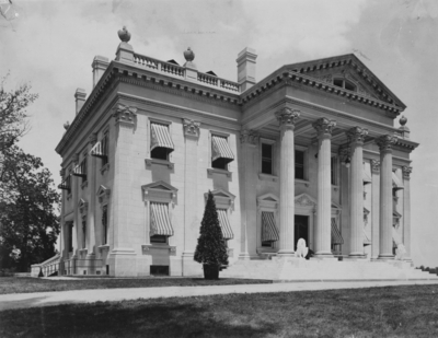Exterior of Elmendorf Farm Mansion; the construction and landscaping begun in #7 are finished, the completed two story mansion boasts a tidy walkway and well manicured grass, the steps are guarded by two stone lions. Silver Print