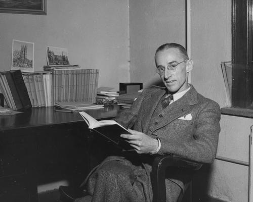Cooke, Arthur Louis, Professor of Literature, English Department, pictured with copy of an edition of the plays of Nathaniel Lee, edited by Cooke and faculty member Thomas B. Stroup