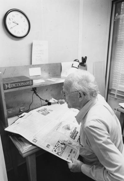 Crabb, Alfred L., Jr., Professor, English Education Department, pictured reading newspaper over the radio for a program intended for blind listeners, 