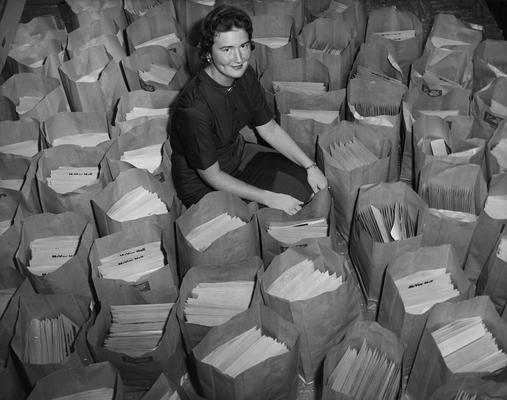 Eaves, Hilma, Secretary, Office of the Dean of Men, pictured with information packets for incoming freshmen, Public Relations Department