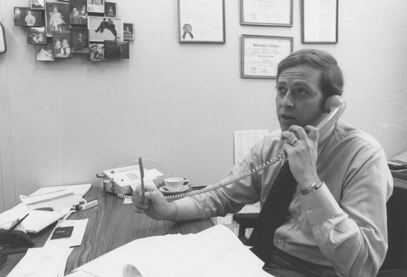 Harkins, William, 1960 alumnus seated at his desk
