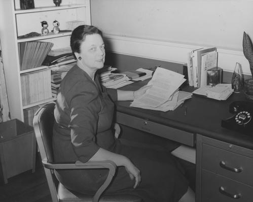 Haselden, Jane, seated at the desk in her office